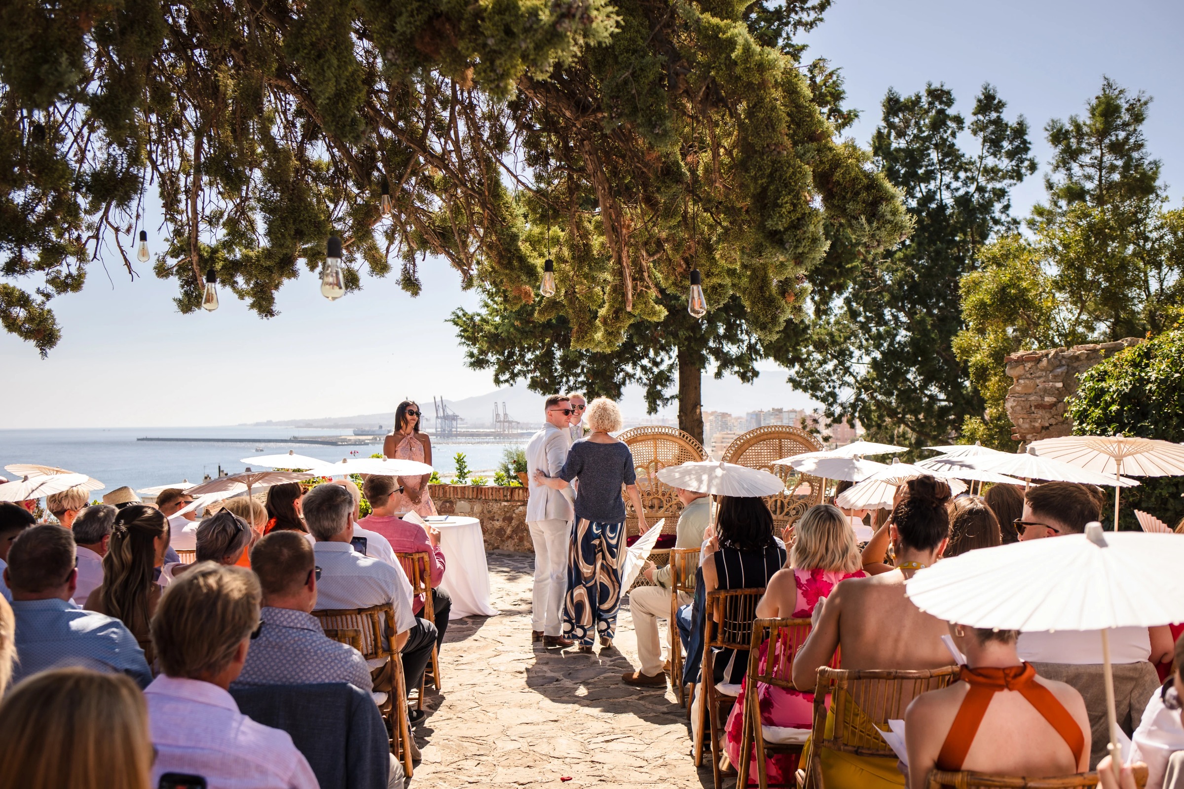 Bride and groom exchanging vows or being announced to seated guests under tree shade at outdoor ceremony. — Wedding at Hotel Only You, Malaga, spain