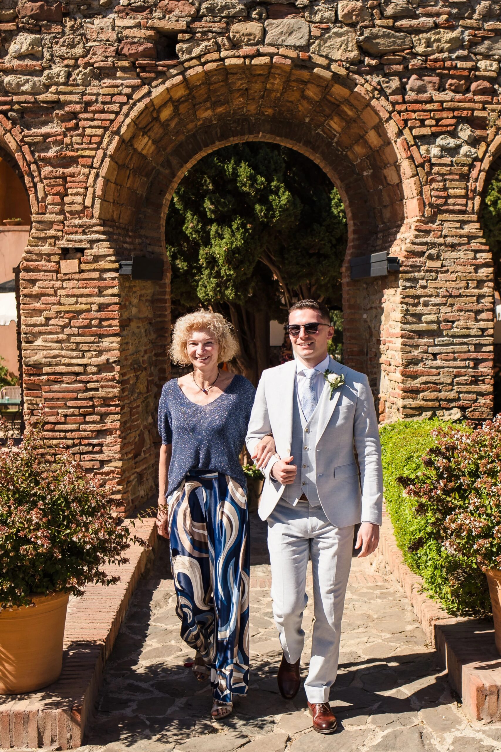 Couple walking arm-in-arm through a stone archway in bright sunlight — Wedding at Hotel Only You, Malaga, spain