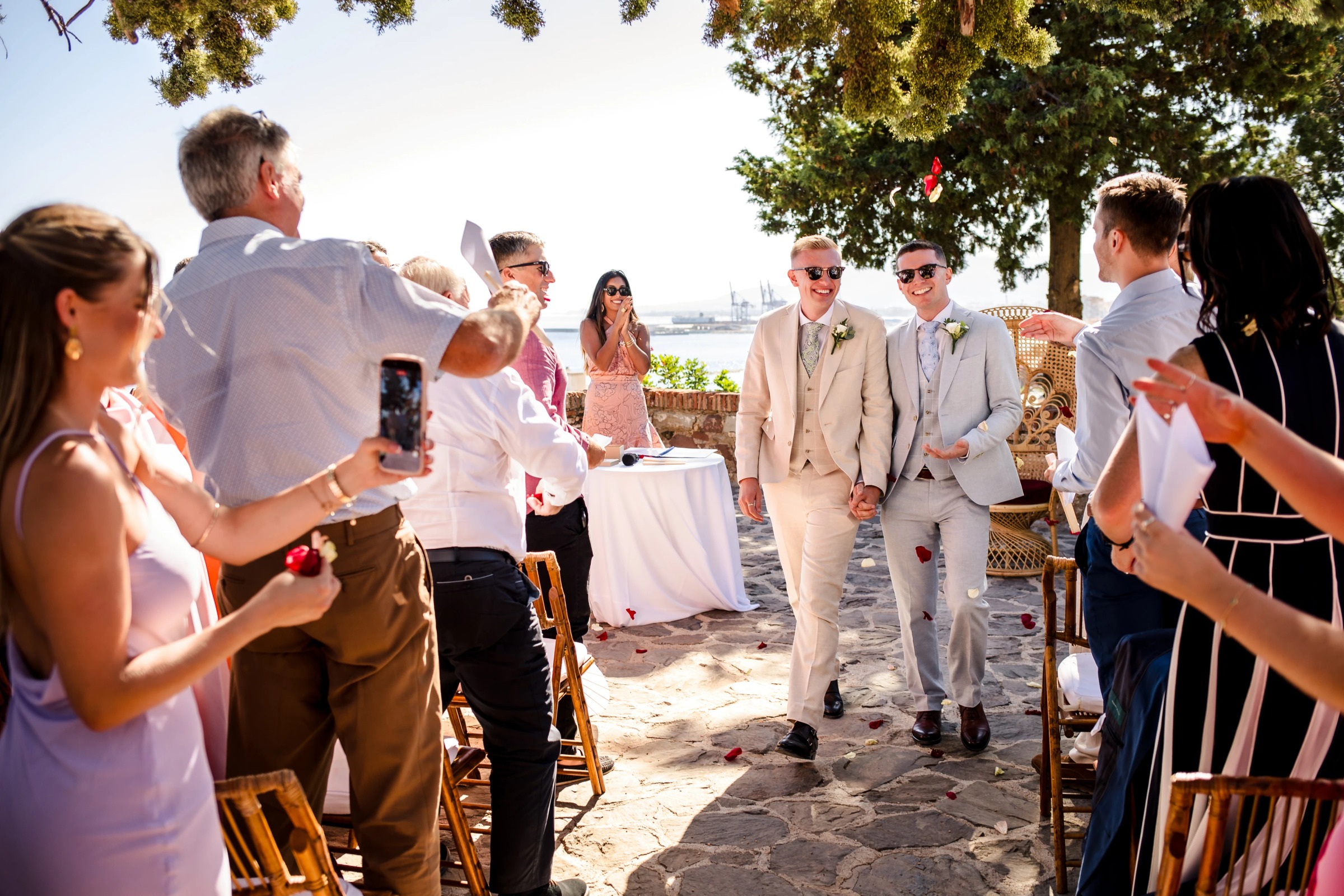 Groom and groomsman walking down an aisle lined with guests holding sparklers and phones. — Wedding at Hotel Only You, Malaga, spain