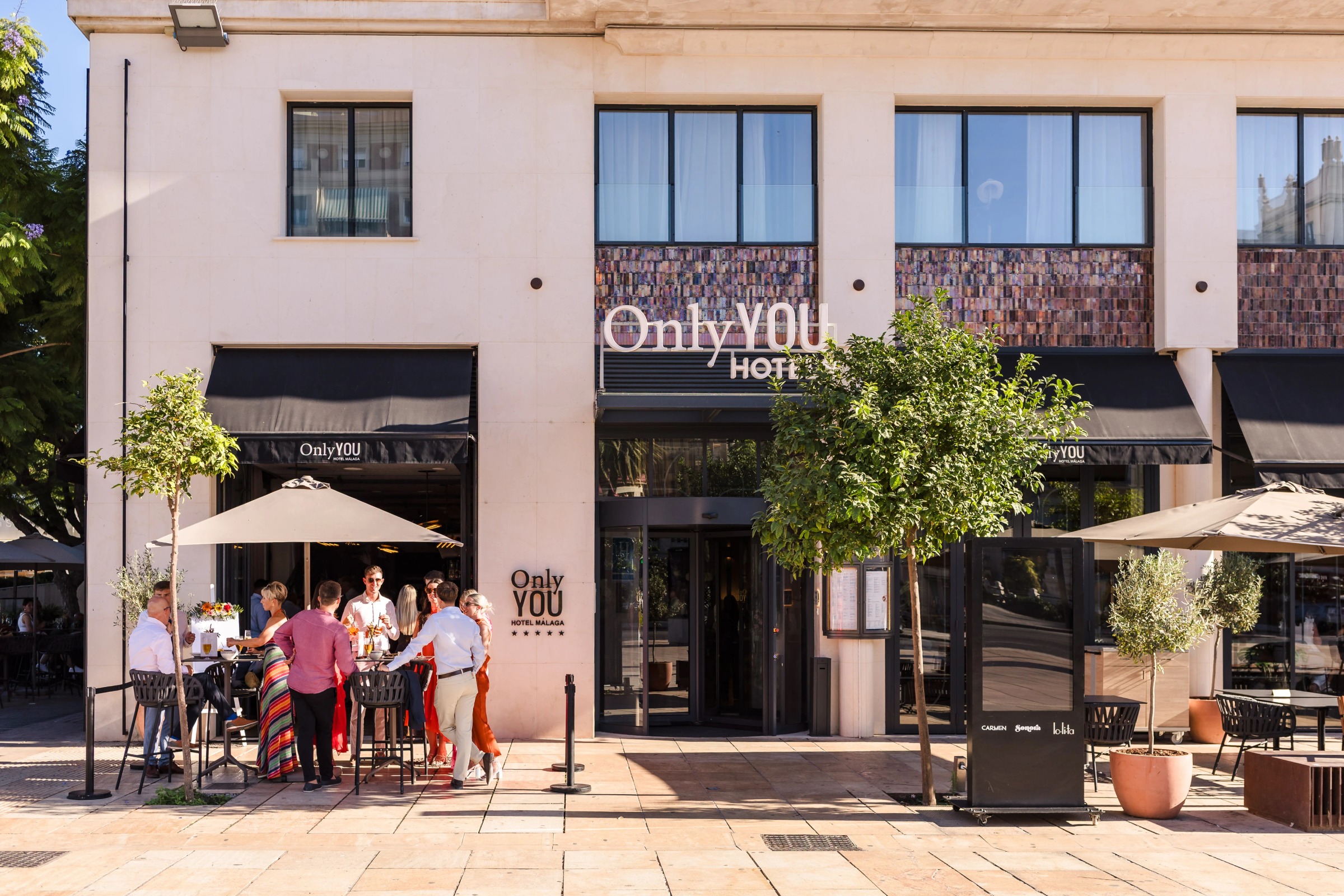 Guests socializing at outdoor café tables in front of a hotel entrance. — Wedding at Hotel Only You, Malaga, spain