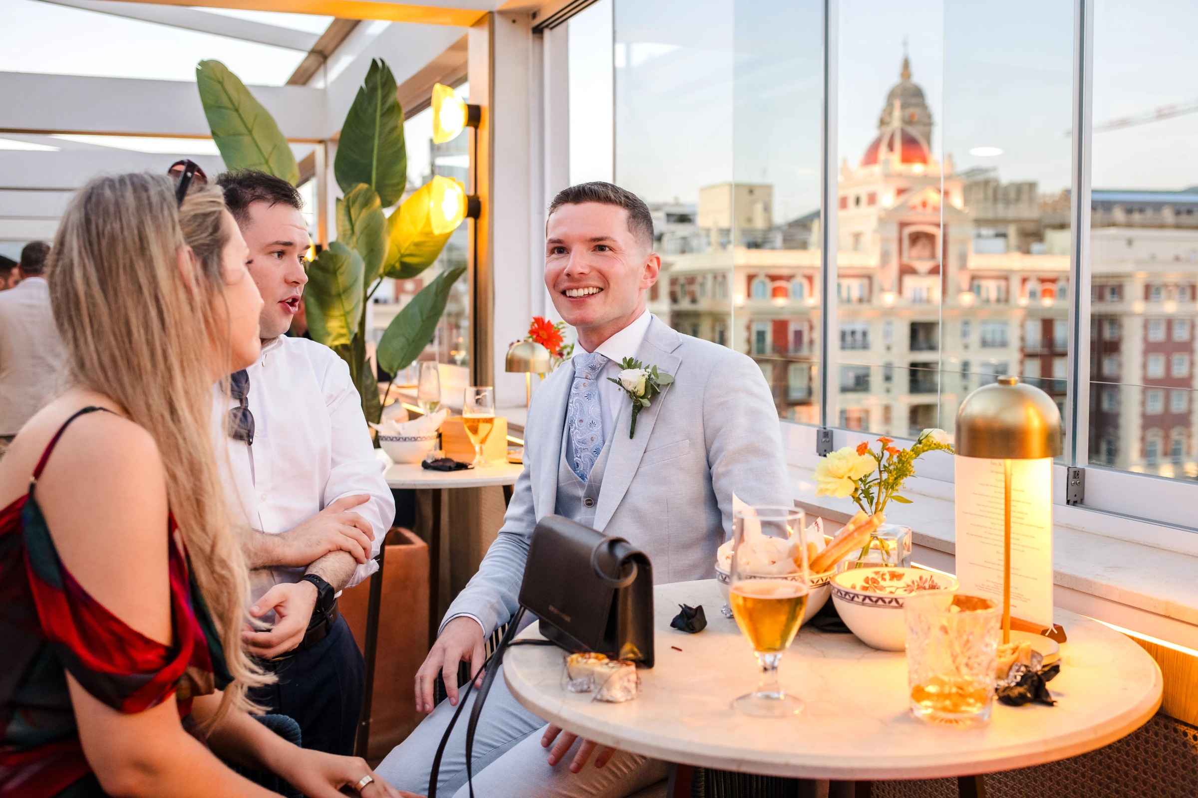 Three guests conversing and laughing at a high-rise cocktail reception, holding drinks and enjoying appetizers. — Wedding at Hotel Only You, Malaga, spain
