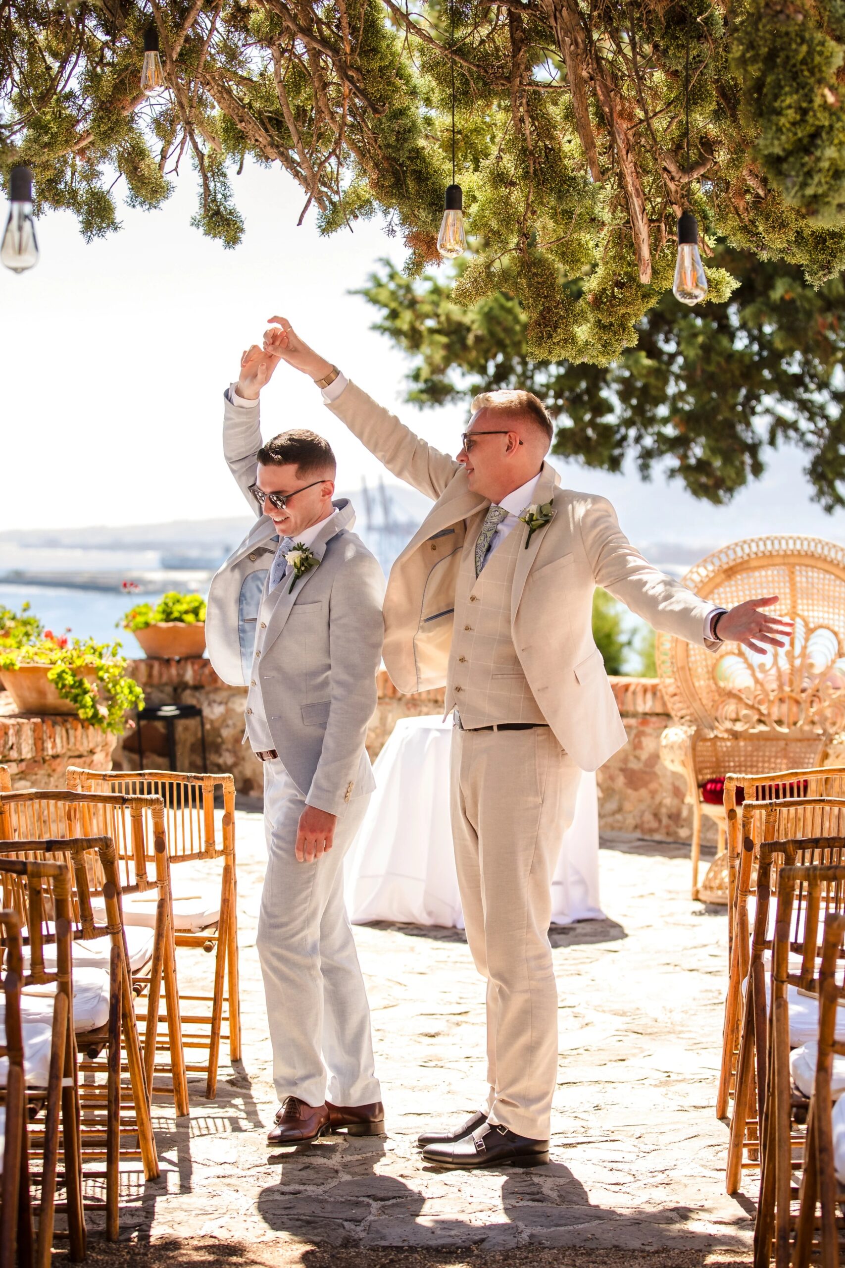 Two grooms raise their joined hands in celebration during their wedding ceremony. — Wedding at Hotel Only You, Malaga, spain