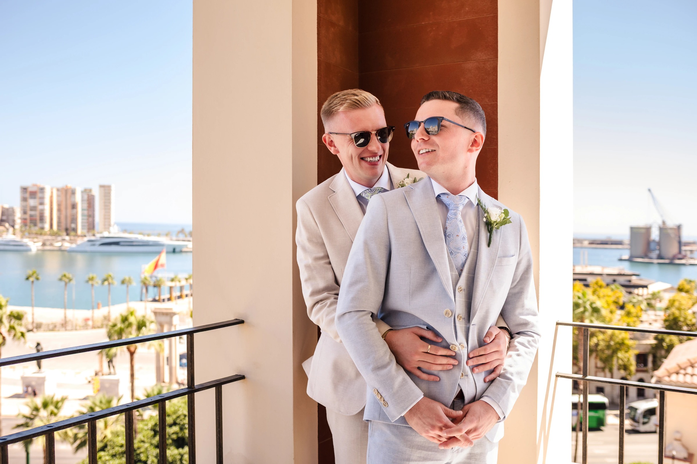 Two grooms stand together on a balcony, smiling at each other in their wedding attire. — Wedding at Hotel Only You, Malaga, spain
