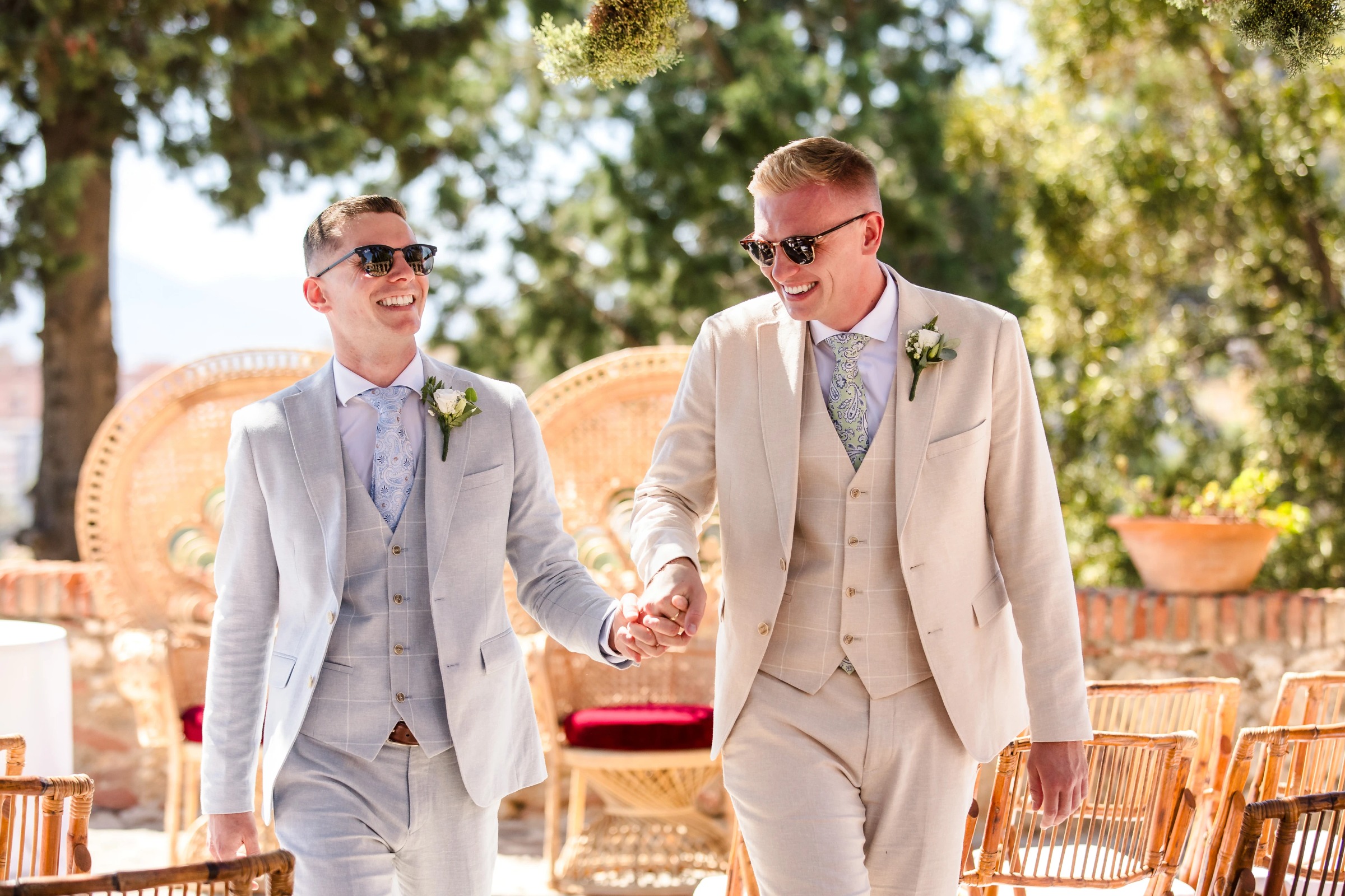 Two grooms walk hand in hand through an outdoor wedding venue, smiling at each other. — Wedding at Hotel Only You, Malaga, spain