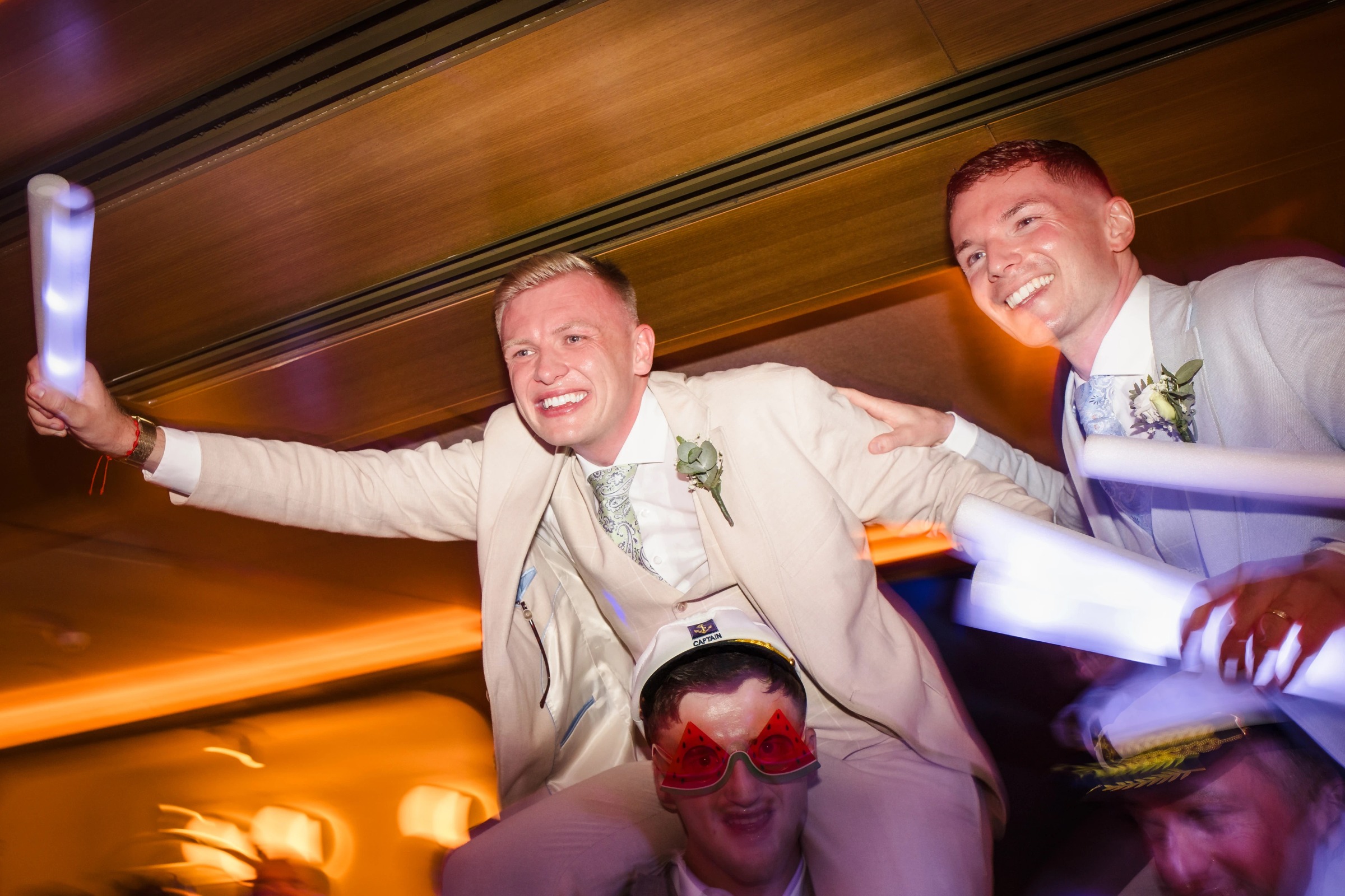 Two men in cream suits celebrate exuberantly at a reception, arms raised and smiling widely. — Wedding at Hotel Only You, Malaga, spain