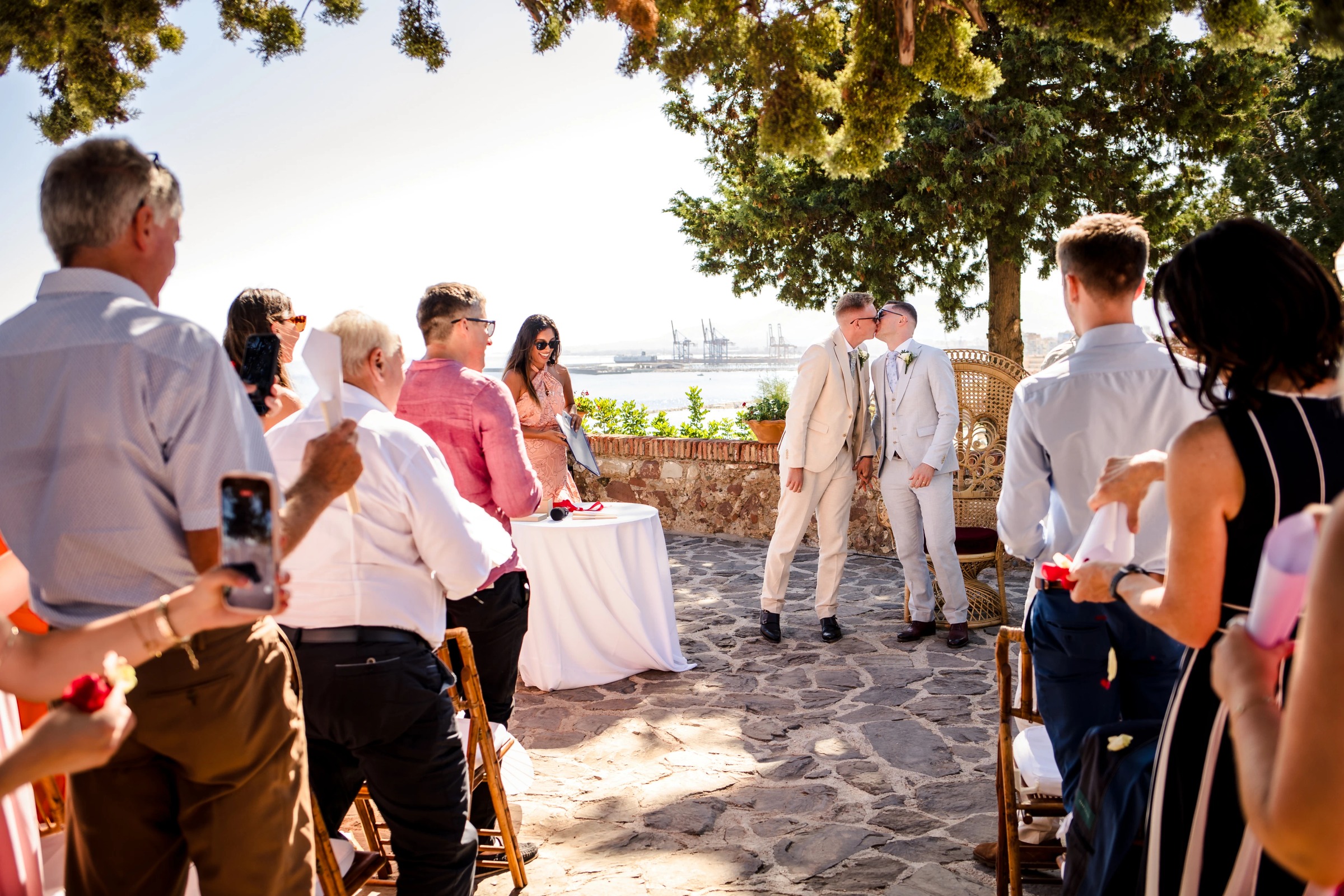 Wedding guests mingling and conversing during an outdoor ceremony or reception gathering beneath shade trees. — Wedding at Hotel Only You, Malaga, spain